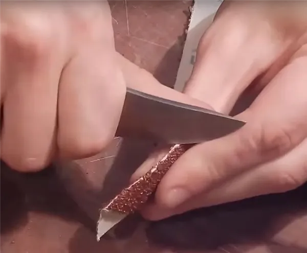 Соскабливаем часть абразива ножом со сгиба ленты.